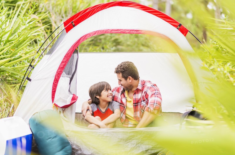Father and son (12-13) sitting in tent