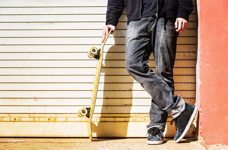 Man with skateboard leaning on garage door
