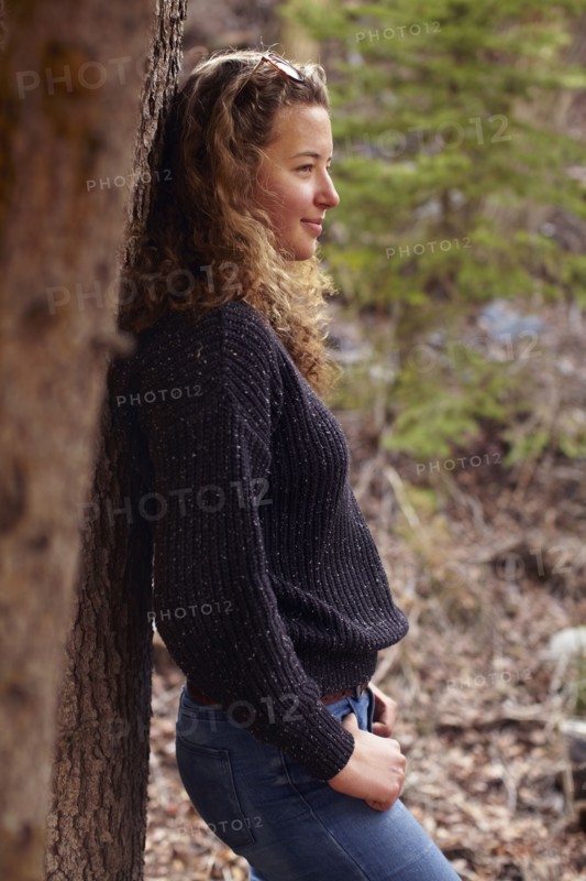 Portrait of young woman leaning on tree