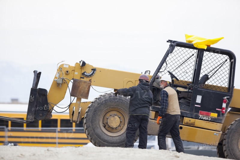 Two men standing next to earthmover