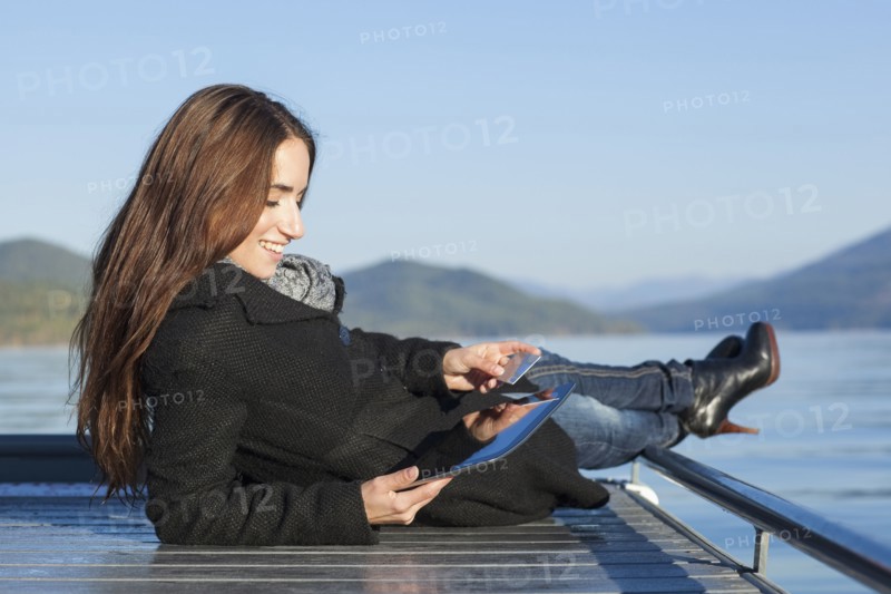Woman with tablet by lake