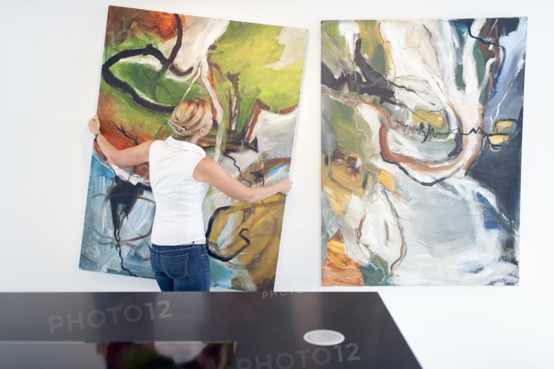 Woman hanging paintings indoors