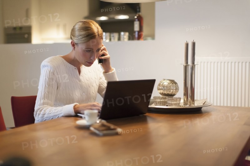 Woman using laptop and cell phone at home