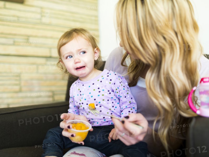Woman feeding her daughter (12-17 months)