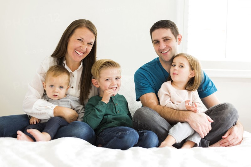 Portrait of family with three children (2-3, 4-5) sitting on bed