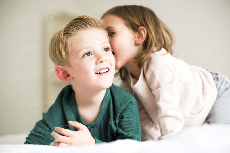 Siblings (2-3, 4-5) whispering in bedroom