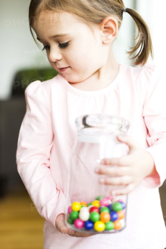 Girl (4-5) holding glass jar with candies