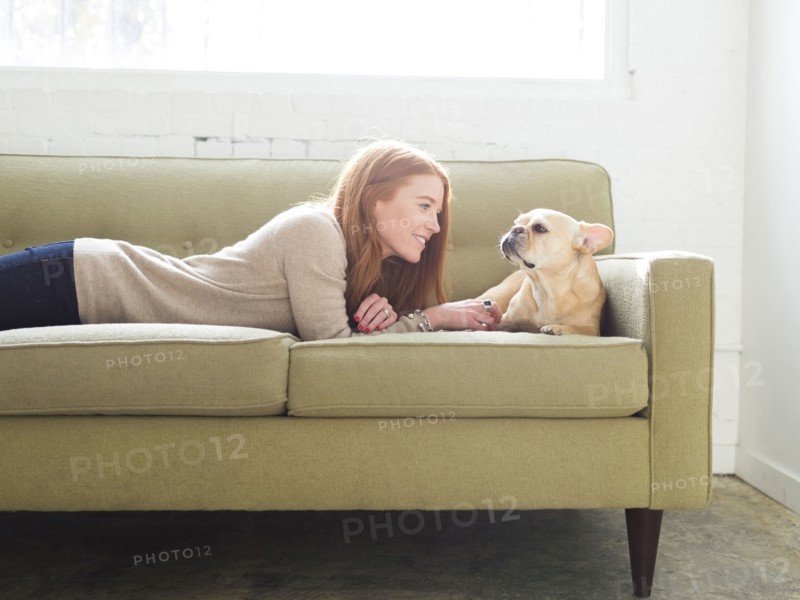Woman and pug lying on sofa