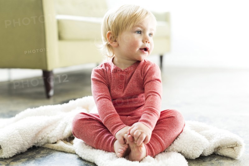 Baby boy (2-3) sitting on blanket in living room