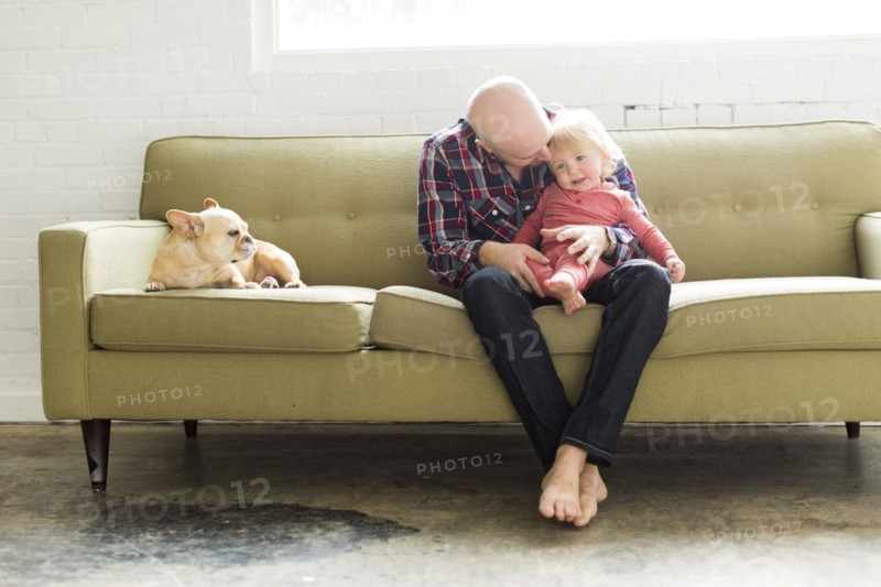 Father sitting on sofa embracing baby son (2-3)