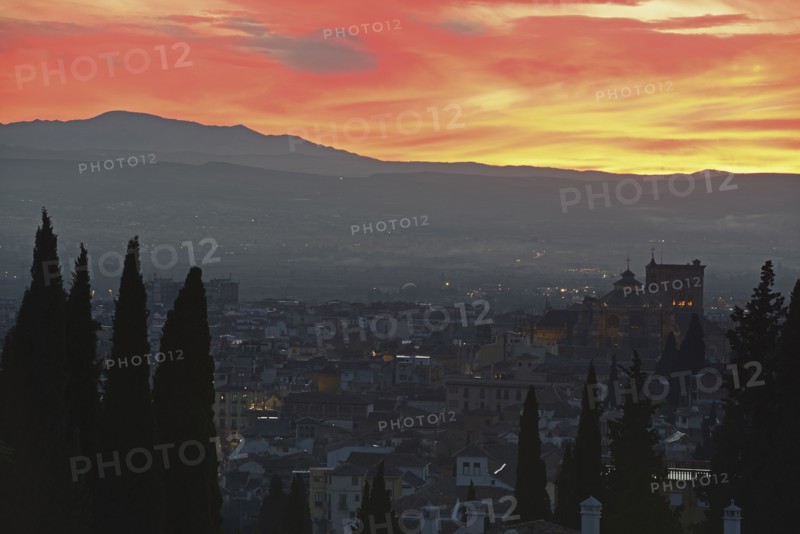 Cityscape and hill at sunset, red yellow sky