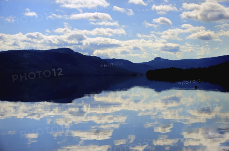 Symmetrical view of blue sky and clouds reflecting in lake