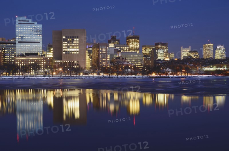 Illuminated cityscape reflecting in water at dusk