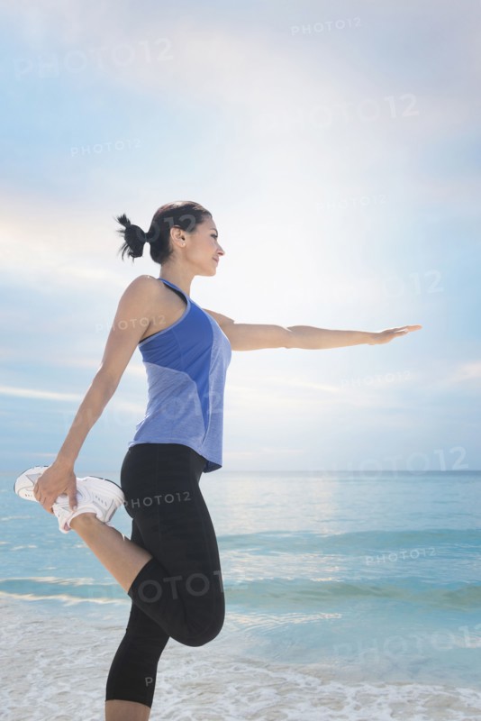 Young woman exercising by sea.