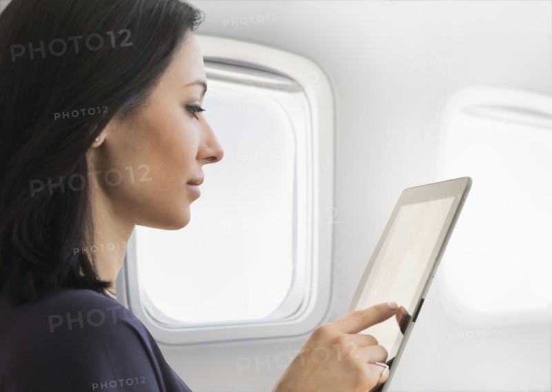 Young woman using tablet on plane.