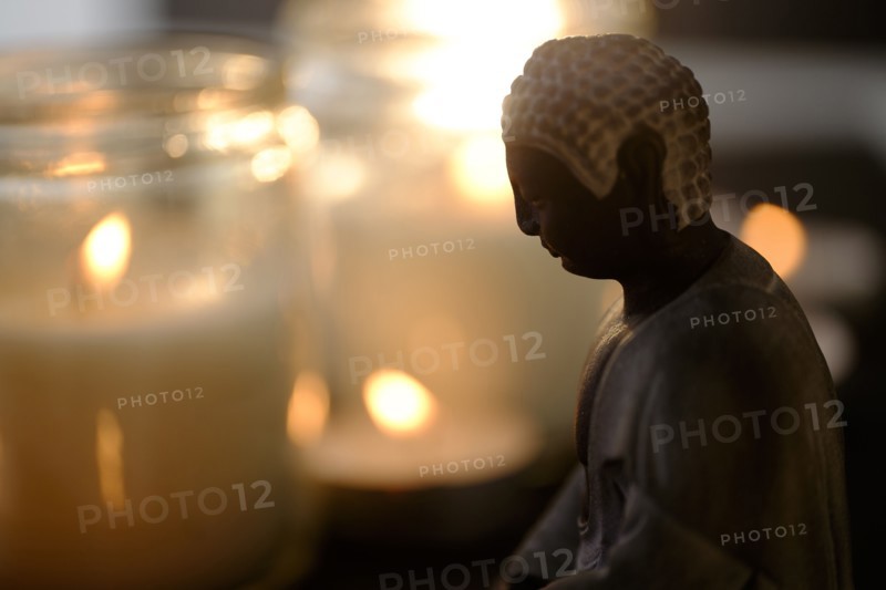 Burning candles with Buddha figurine in foreground.