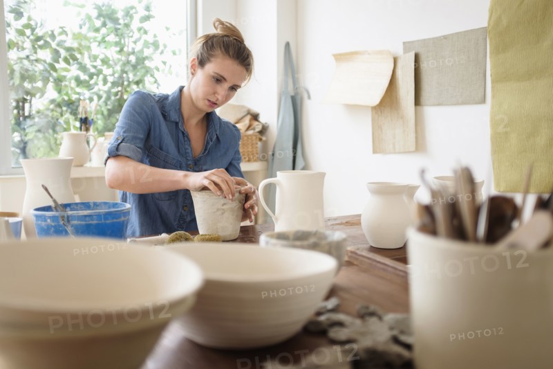 Young woman making pottery in studio.