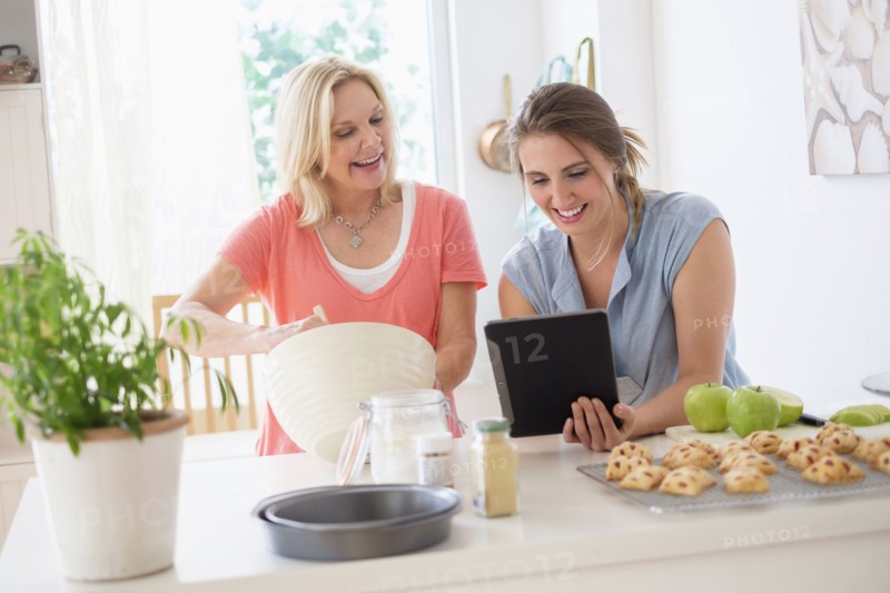 Mother with adult daughter baking in kitchen.