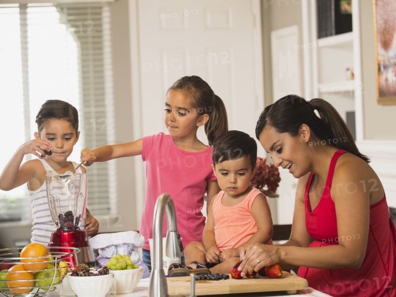 Mother and children (2-3, 6-7, 8-9) preparing fruit cocktails