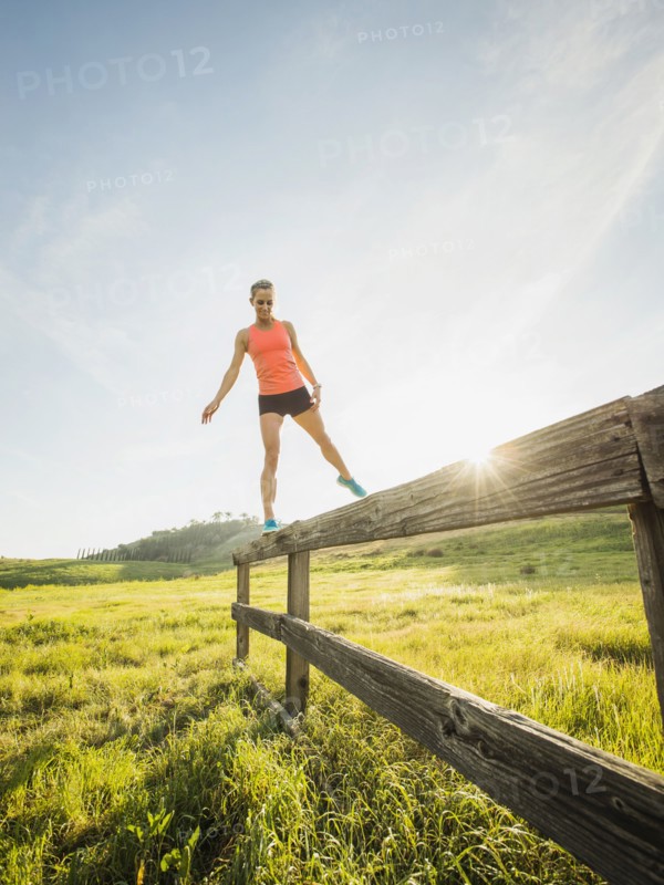 Woman balancing on wooden fence