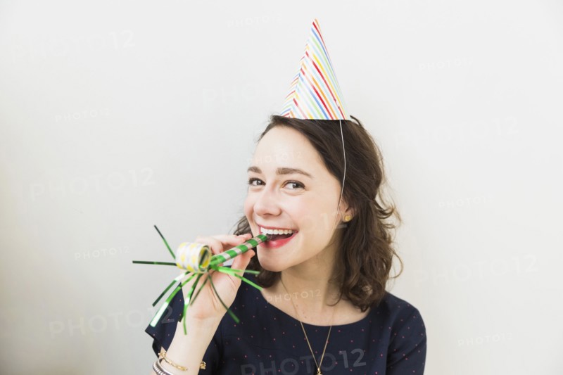 Smiling young woman with party horn blower
