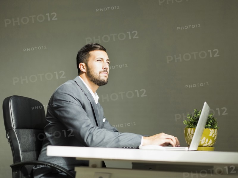 Young man sitting at desk and using laptop