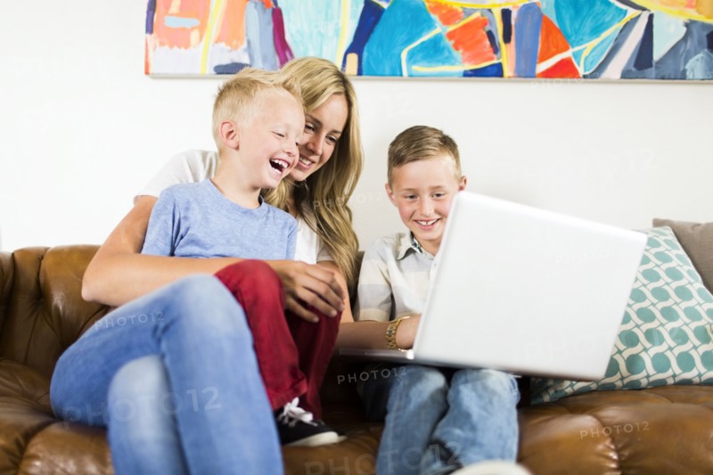 Mother with children (4-5, 6-7) using laptop on sofa