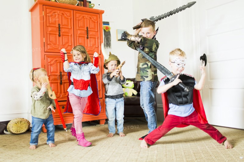Children (2-3, 4-5, 6-7) wearing superhero costumes playing at home
