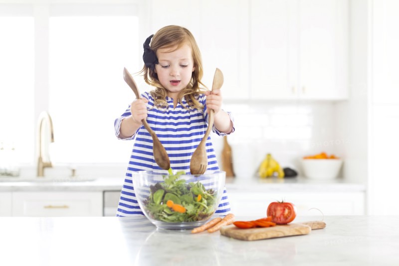 Girl (4-5) mixing salad