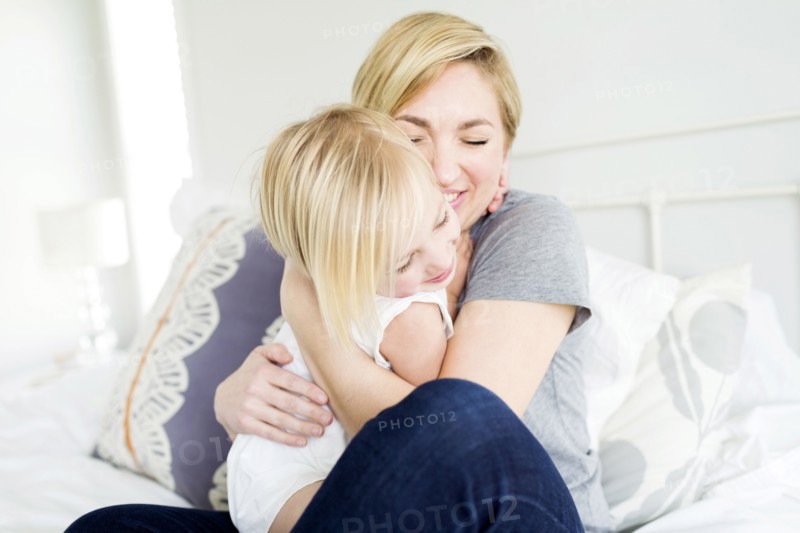 Woman hugging daughter (2-3) in bedroom