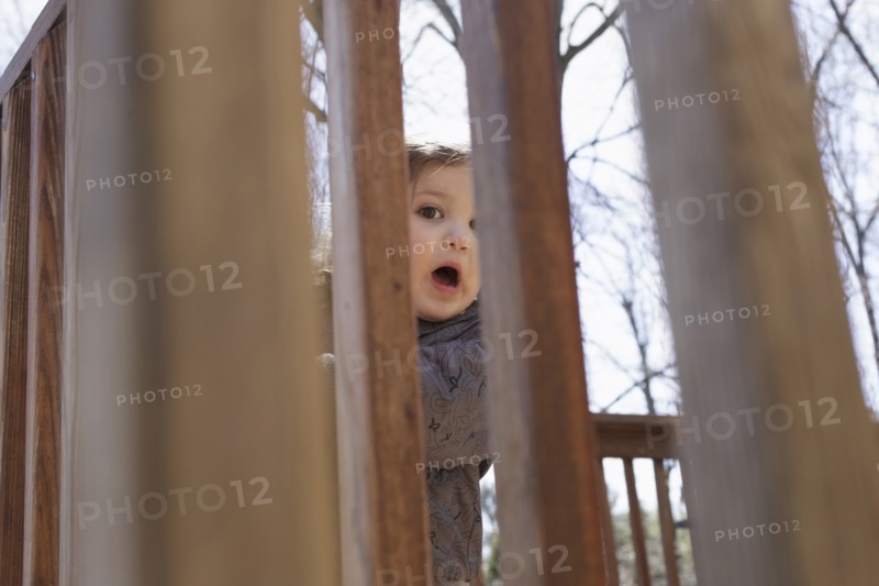 Portrait of girl hiding behind fence