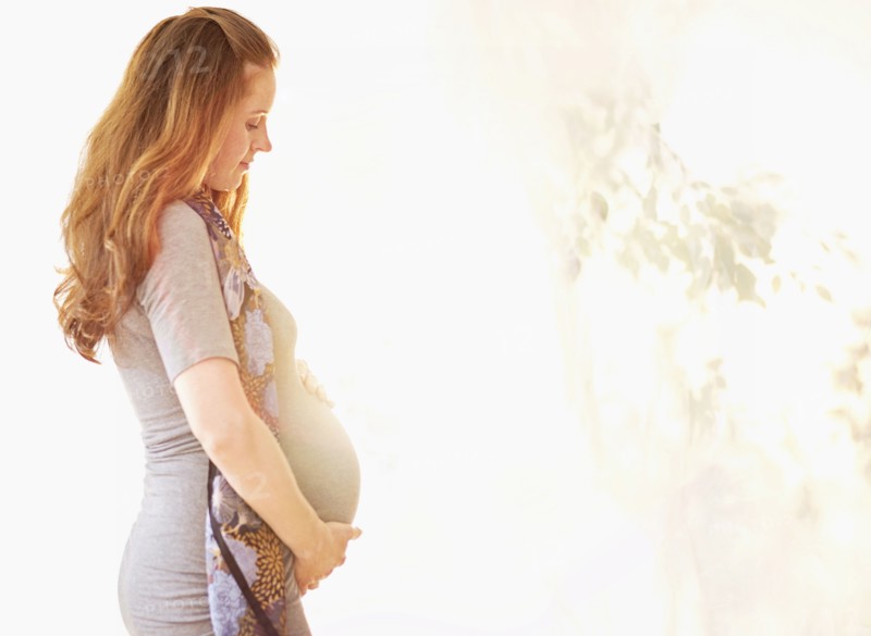 Side view of pregnant woman outdoors.
