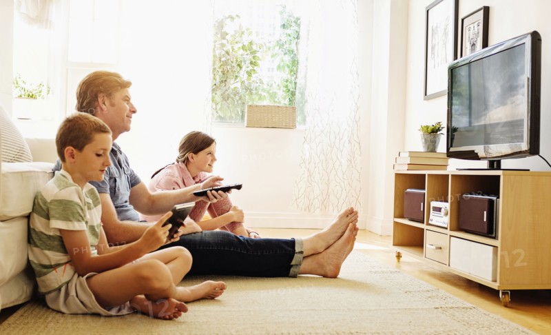 Children (8-9, 10-11) watching TV with their father.