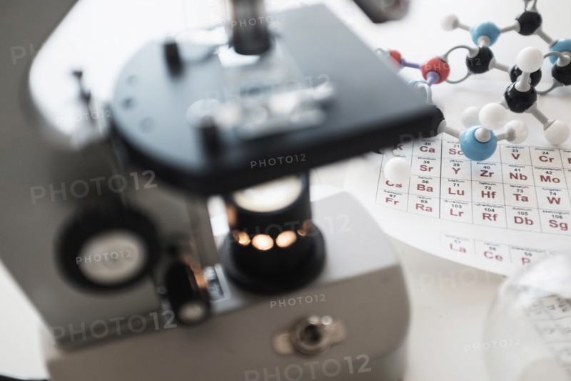 Periodic table and microscope on desk.
