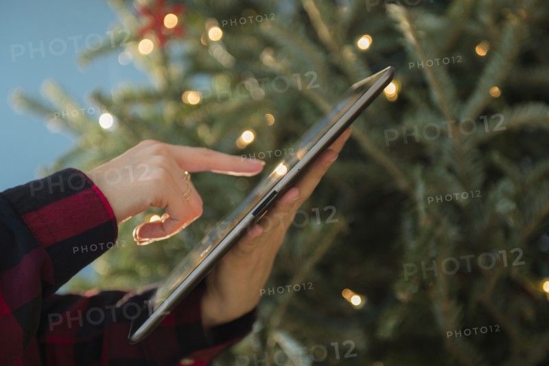 Person using tablet near Christmas tree
