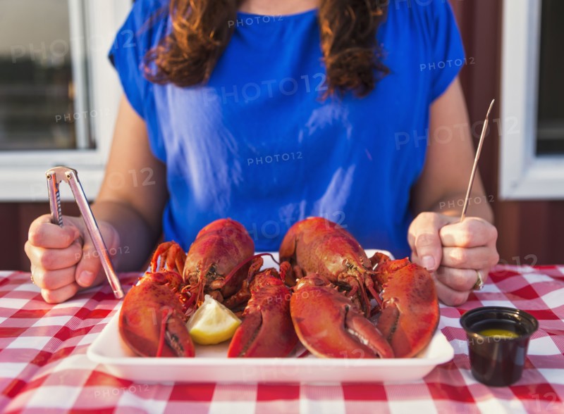 View of table with lobster meal and woman preparing to eat