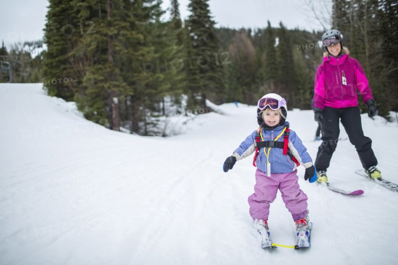 Little girl (2-3) learning skiing with mother