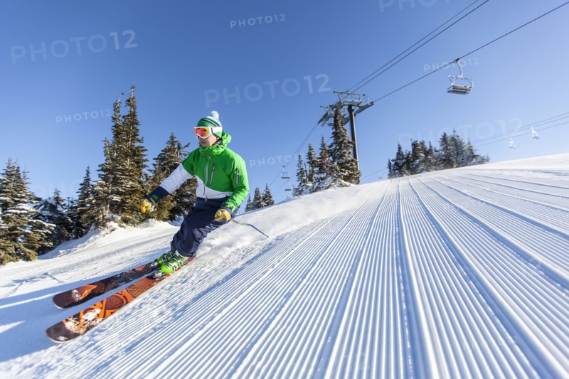 Mature man on ski slope under blue sky