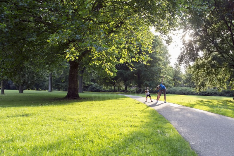 Mother and son (12-13) exercising in park