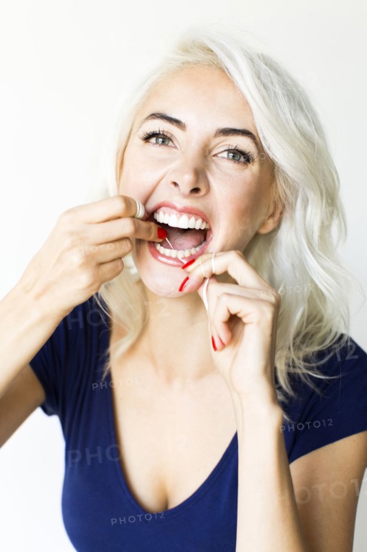 Studio shot of woman using dental floss