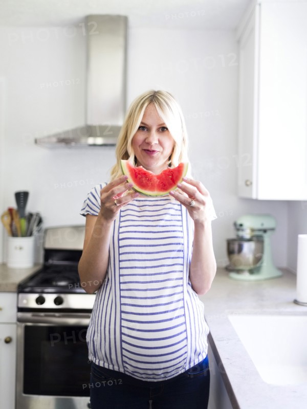 Pregnant woman holding slice of watermelon