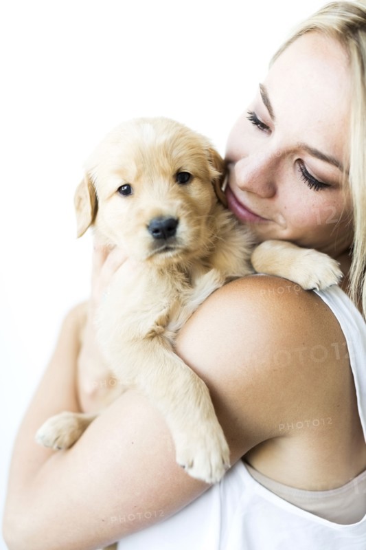 Studio shot of woman holding Golden Retriever puppy in arms