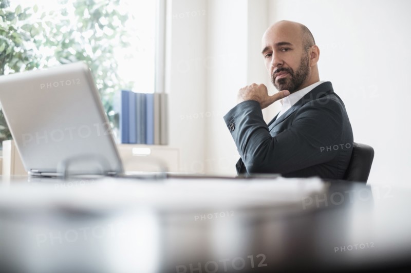 Serious businessman sitting at desk in office.