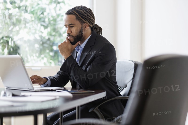 Concentrated businessman working with laptop at desk in office.