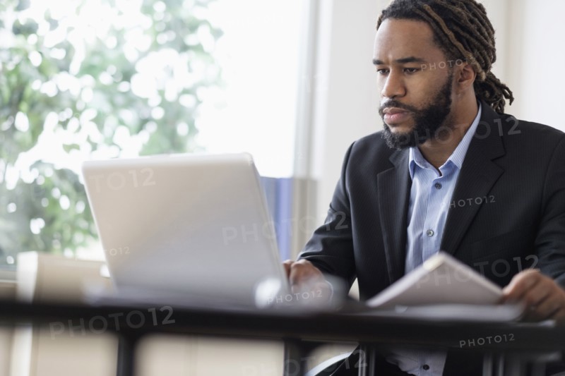 Concentrated businessman working with laptop at desk in office.