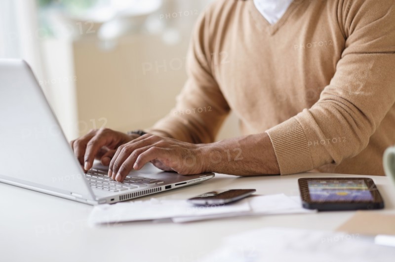 Man working with laptop at table at home.