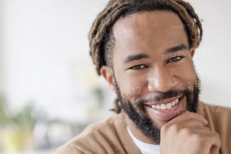 Portrait of smiley young man with hand on chin.