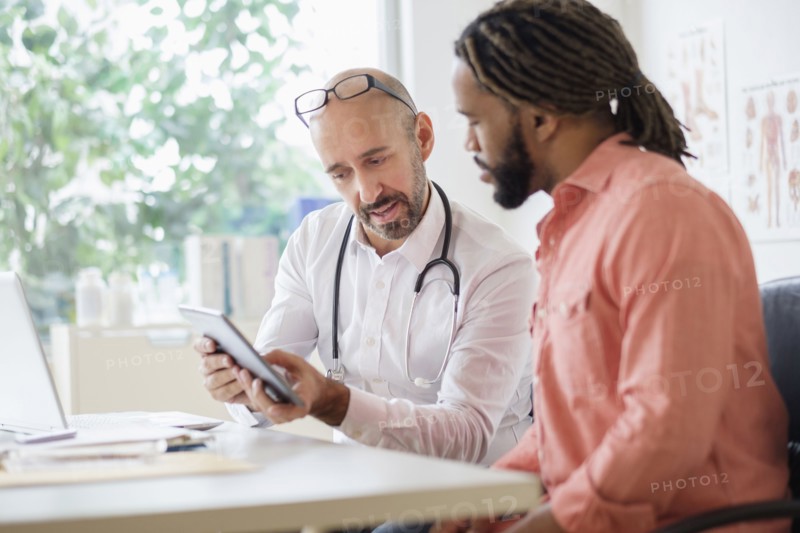 Doctor giving consultation to patient using digital tablet.