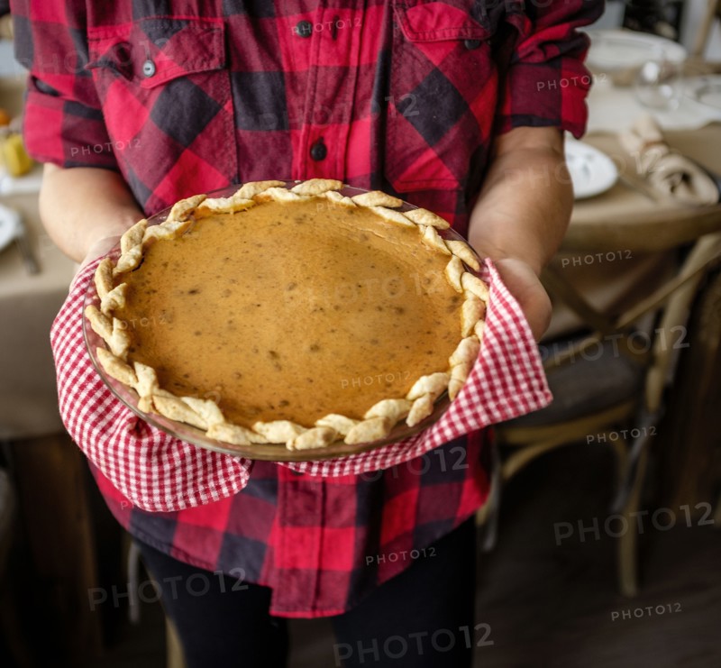 Woman holding baked pumpkin pie for Thanksgiving.