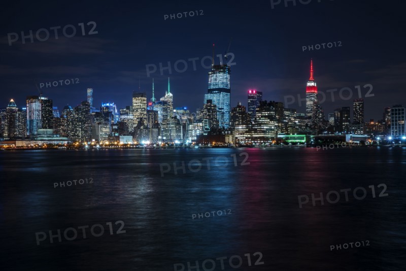 Illuminated cityscape reflecting in river. New York City, New York, USA.